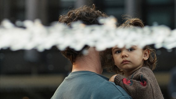 A girl in her father’s arms, with a jet of water in the foreground