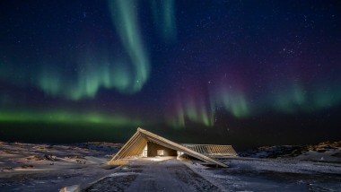 Isfjordcentret i det spektakulära norrskenet i den Grönländska polarnatten (© Adam Mørk)